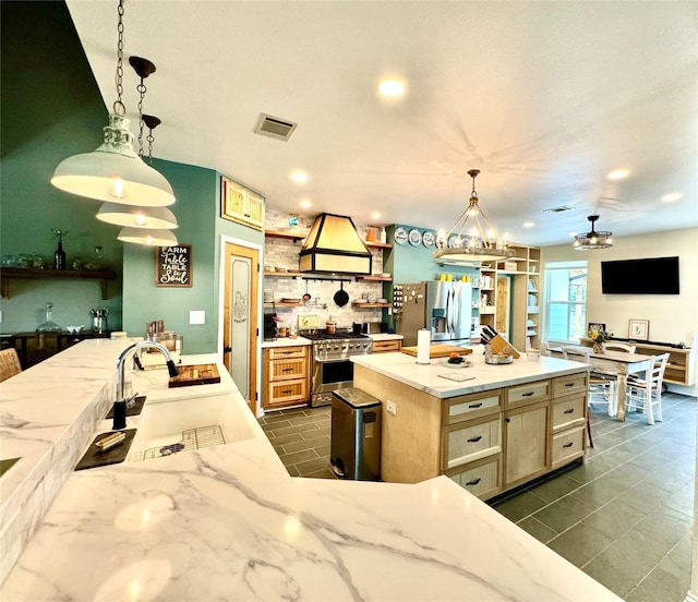 kitchen with sink, pendant lighting, a kitchen island with sink, appliances with stainless steel finishes, and custom exhaust hood