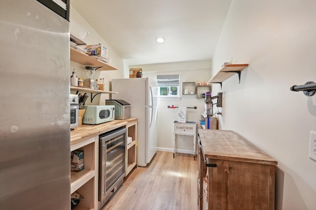 kitchen with light hardwood / wood-style floors, white appliances, beverage cooler, and wooden counters