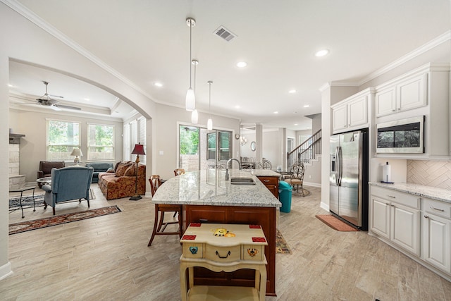 kitchen with stainless steel fridge, a center island with sink, white cabinetry, and sink