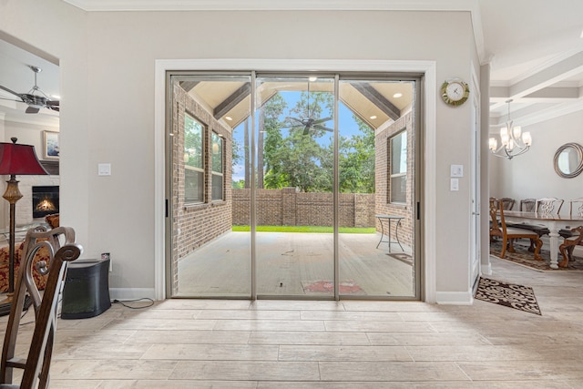 doorway to outside with vaulted ceiling, light hardwood / wood-style floors, an inviting chandelier, and ornamental molding