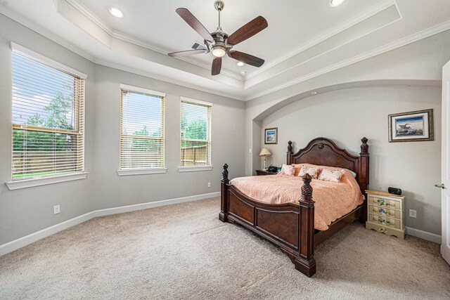 carpeted bedroom featuring ceiling fan, ornamental molding, and a tray ceiling