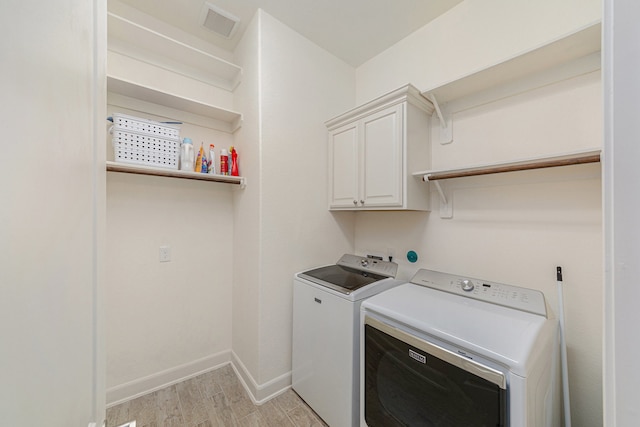 laundry room featuring cabinets, light hardwood / wood-style floors, and washer and clothes dryer