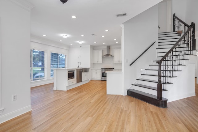 unfurnished living room featuring crown molding and light wood-type flooring