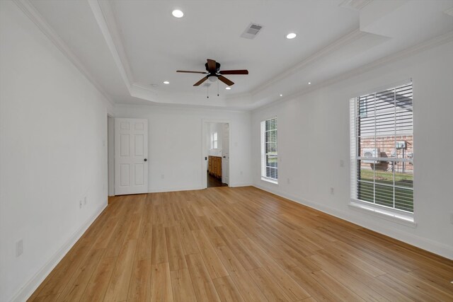 unfurnished living room with a tray ceiling, light hardwood / wood-style flooring, and a healthy amount of sunlight