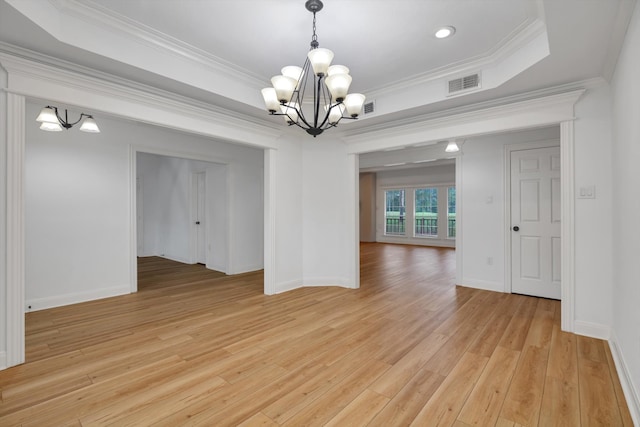 unfurnished dining area featuring a raised ceiling, light hardwood / wood-style floors, an inviting chandelier, and ornamental molding