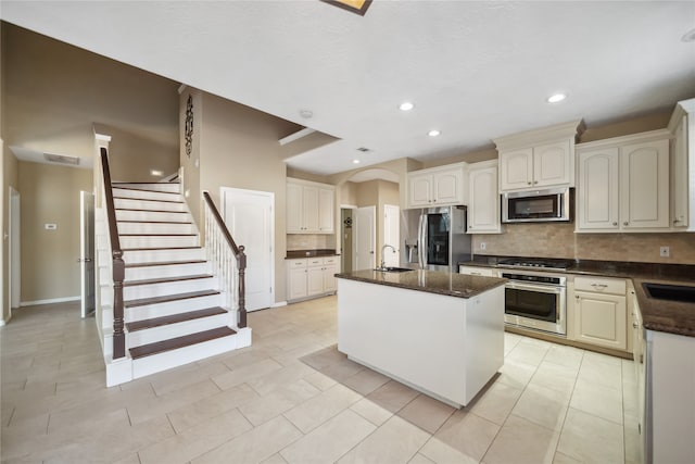 kitchen featuring appliances with stainless steel finishes, backsplash, a center island with sink, and sink