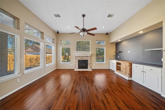 unfurnished living room with a fireplace, ceiling fan, and dark wood-type flooring