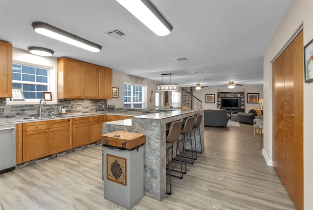 kitchen featuring light hardwood / wood-style floors, ceiling fan, a breakfast bar area, and sink