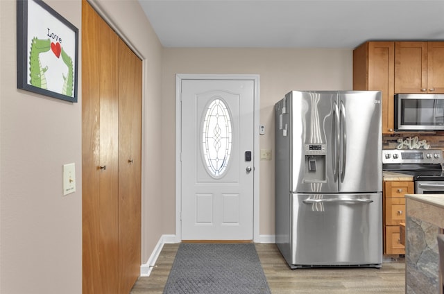 kitchen with backsplash, stainless steel appliances, and light hardwood / wood-style floors