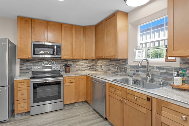 kitchen with appliances with stainless steel finishes, tasteful backsplash, light hardwood / wood-style floors, and sink