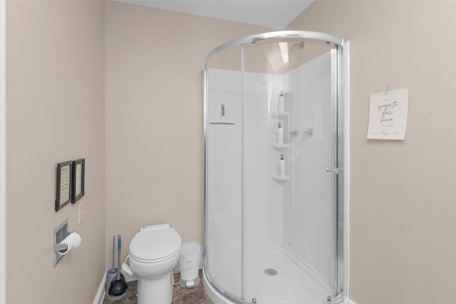 bathroom featuring a shower with door and toilet