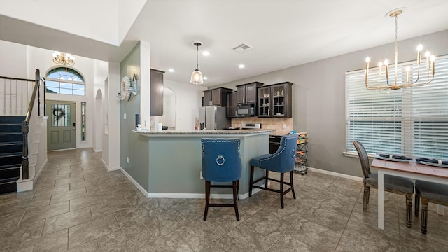 kitchen with an inviting chandelier, a kitchen breakfast bar, decorative light fixtures, stainless steel fridge with ice dispenser, and kitchen peninsula