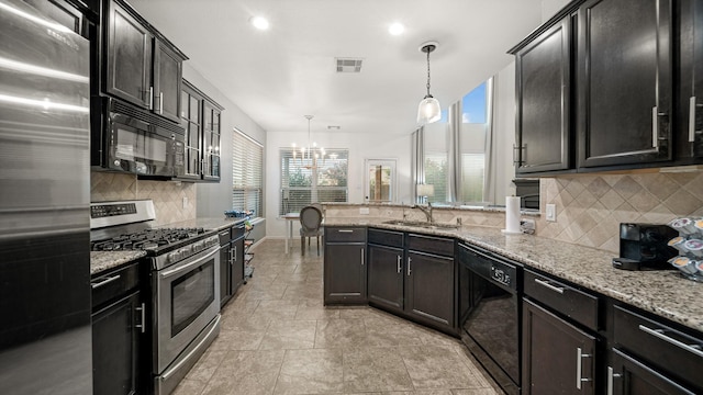 kitchen featuring sink, light stone counters, pendant lighting, black appliances, and decorative backsplash