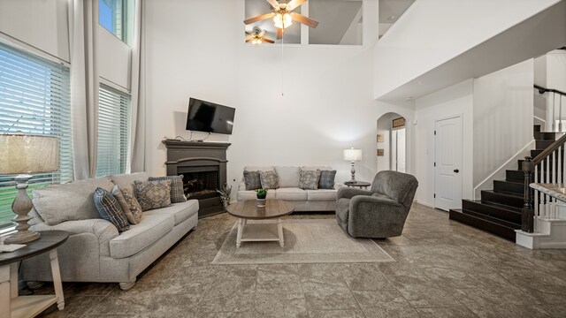 living room with ceiling fan and a towering ceiling