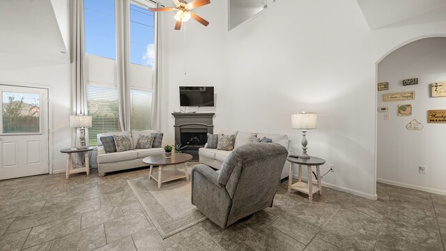 living room featuring ceiling fan, a towering ceiling, and a wealth of natural light