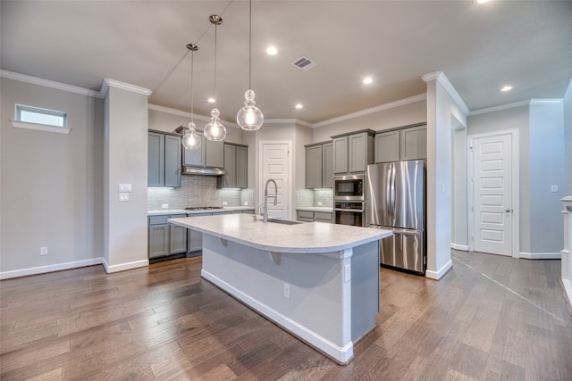 kitchen featuring an island with sink, sink, appliances with stainless steel finishes, and dark wood-type flooring