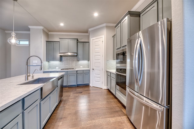 kitchen with backsplash, stainless steel appliances, dark wood-type flooring, sink, and pendant lighting