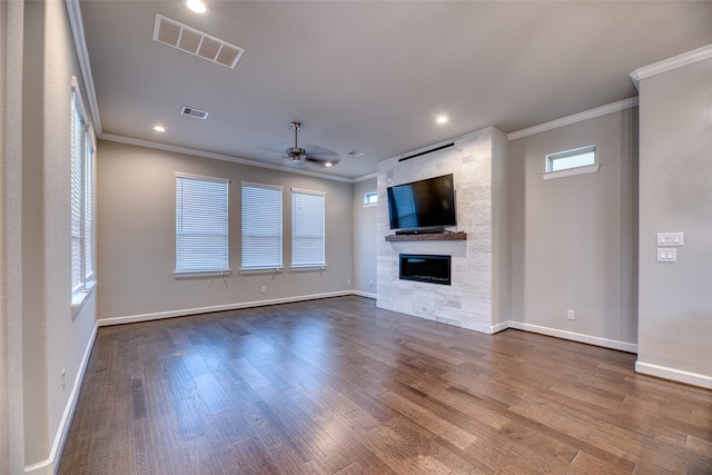 unfurnished living room with hardwood / wood-style floors, a stone fireplace, ceiling fan, and ornamental molding