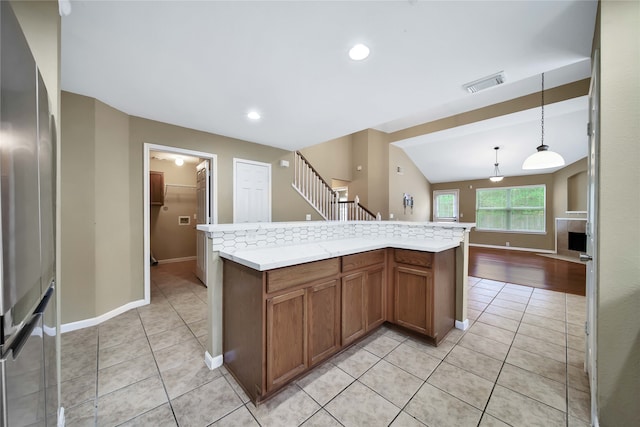 kitchen featuring stainless steel refrigerator, a kitchen island, pendant lighting, vaulted ceiling, and light tile patterned floors