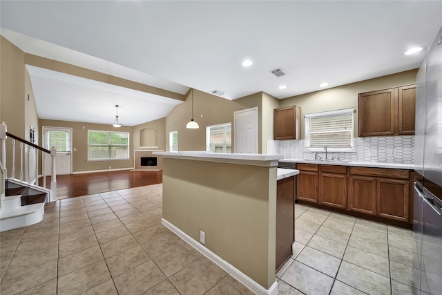 kitchen featuring light tile patterned floors, decorative light fixtures, vaulted ceiling, and tasteful backsplash