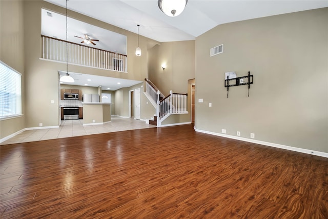 unfurnished living room featuring ceiling fan, light hardwood / wood-style flooring, and high vaulted ceiling