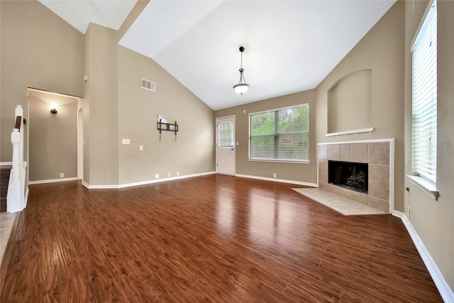 unfurnished living room with vaulted ceiling, dark wood-type flooring, and a tiled fireplace