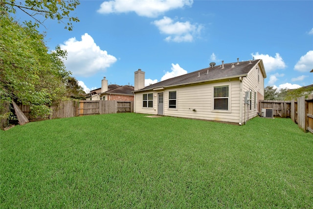 rear view of property featuring a lawn and cooling unit