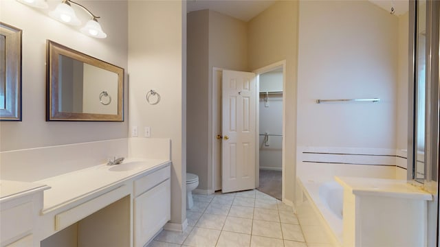 bathroom featuring tile patterned floors, tiled bath, vanity, and toilet