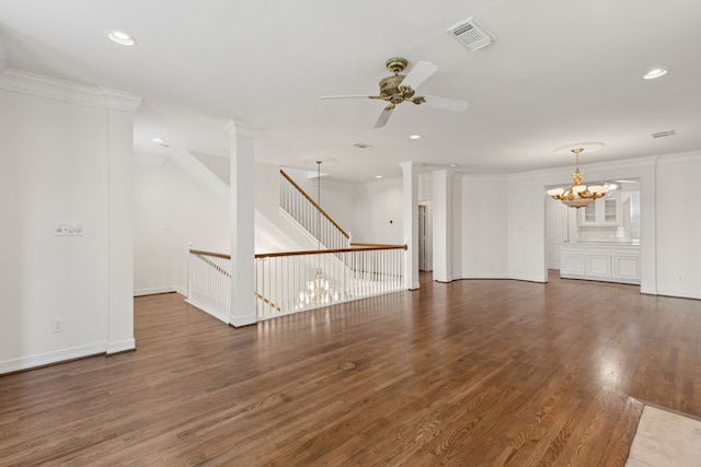 empty room with ceiling fan with notable chandelier, ornamental molding, ornate columns, and dark hardwood / wood-style floors