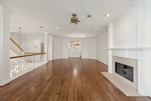 unfurnished living room with hardwood / wood-style floors, ornamental molding, ornate columns, and a tiled fireplace