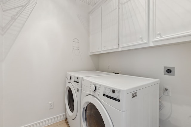 clothes washing area with cabinets and washer and clothes dryer