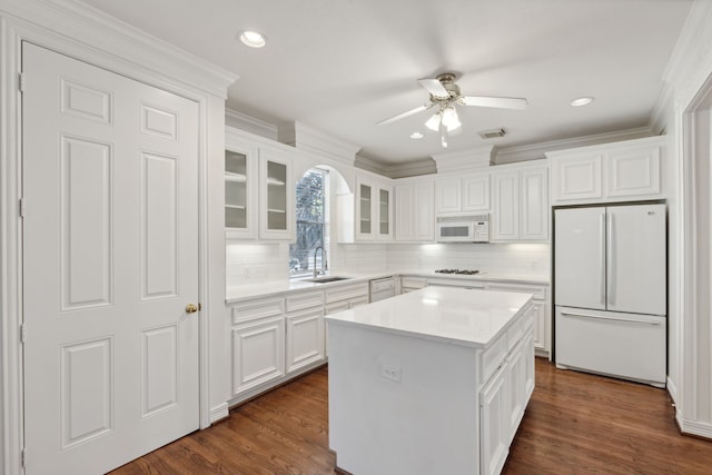 kitchen with white cabinets, sink, a kitchen island, white appliances, and dark wood-type flooring