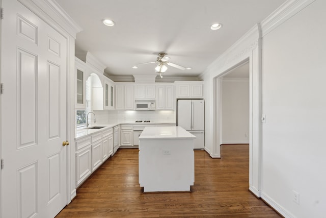 kitchen featuring ornamental molding, white cabinets, dark hardwood / wood-style flooring, white appliances, and a center island