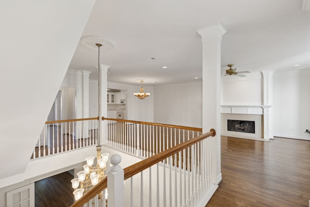 hall with ornamental molding, an inviting chandelier, dark hardwood / wood-style floors, and decorative columns