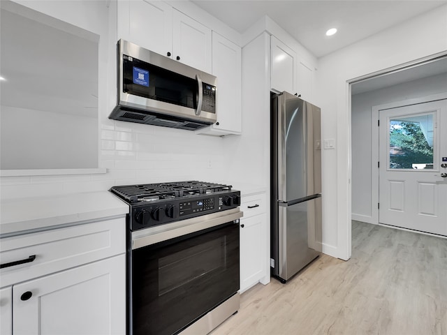 kitchen with white cabinets, backsplash, stainless steel appliances, and light hardwood / wood-style flooring