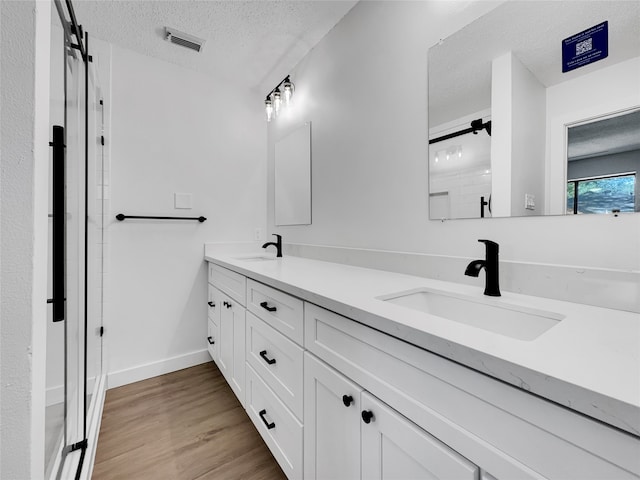 bathroom with vanity, hardwood / wood-style flooring, and a textured ceiling