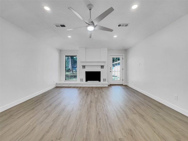 unfurnished living room with a brick fireplace, light hardwood / wood-style flooring, and ceiling fan