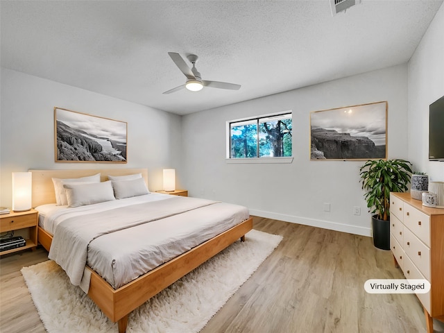 bedroom with ceiling fan, light wood-type flooring, and a textured ceiling