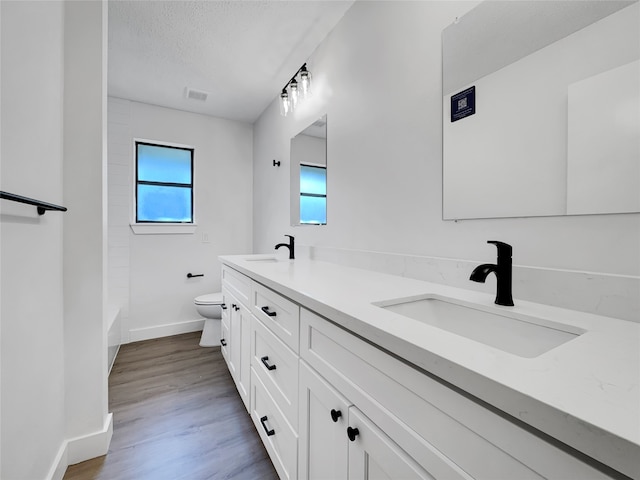 full bathroom featuring vanity, a textured ceiling, washtub / shower combination, hardwood / wood-style floors, and toilet