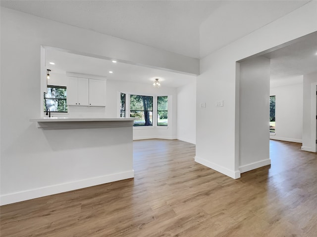 kitchen with kitchen peninsula, light wood-type flooring, and white cabinetry