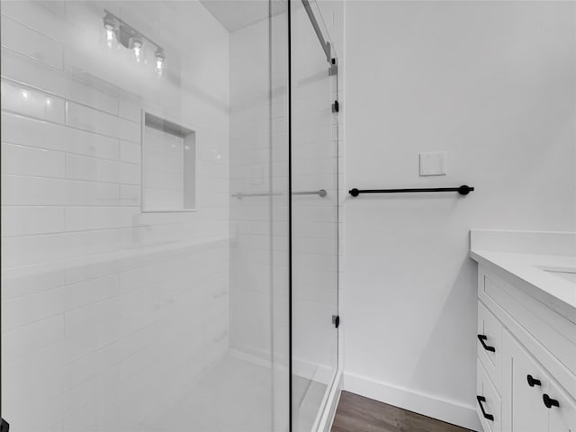 bathroom featuring vanity, hardwood / wood-style floors, and a tile shower