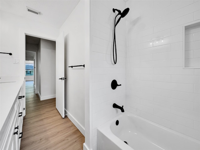 bathroom featuring vanity, wood-type flooring, and tiled shower / bath