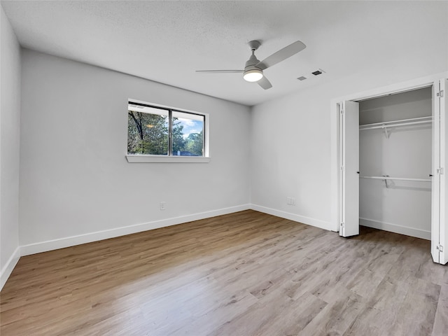 unfurnished bedroom featuring a textured ceiling, a closet, light hardwood / wood-style flooring, and ceiling fan