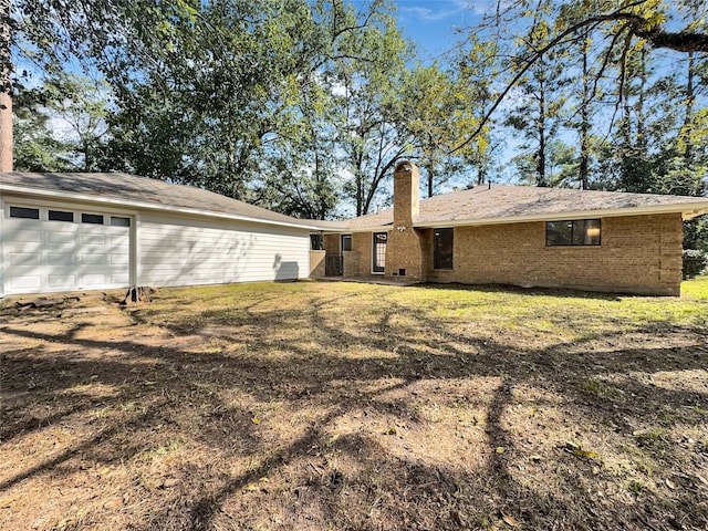 back of property with a lawn and a garage