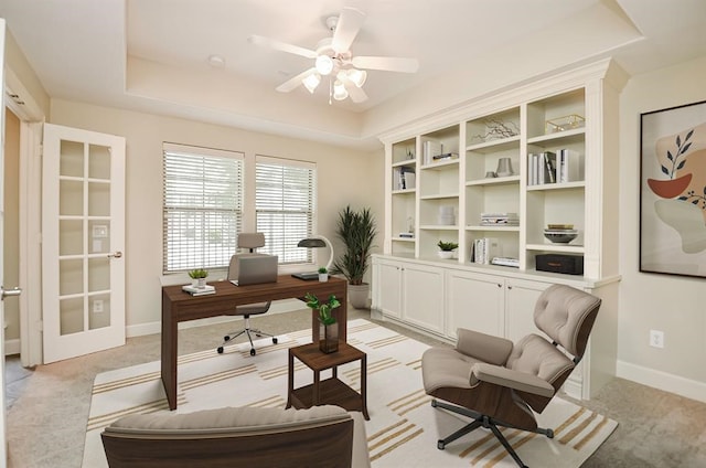 office space featuring light colored carpet, a raised ceiling, and ceiling fan