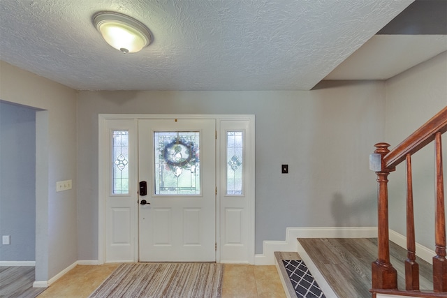 entryway with light tile patterned floors and a textured ceiling