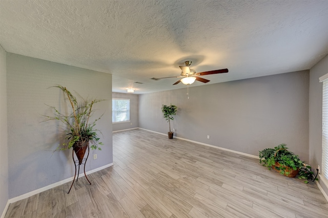 spare room featuring ceiling fan, light hardwood / wood-style flooring, and a textured ceiling