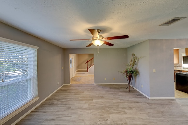 empty room featuring ceiling fan, light hardwood / wood-style floors, and a textured ceiling