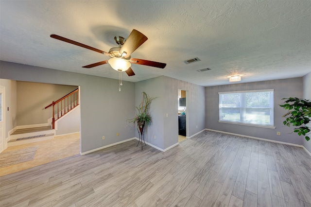 spare room with a textured ceiling, light hardwood / wood-style floors, and ceiling fan