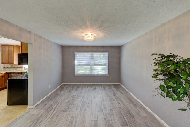 unfurnished dining area featuring a textured ceiling and light wood-type flooring